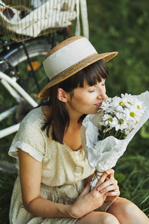 Outdoor fashion portrait of attractive young brunette in a hat on a bicycle.の写真素材