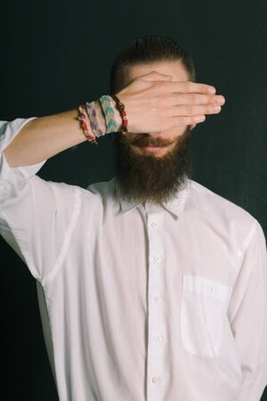 Hipster style bearded man white shirt in studio over black background