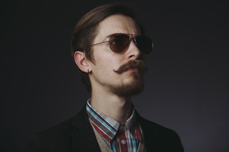Studio portrait of a serious young businessman wearing a black suit on black background, copy spaceの写真素材