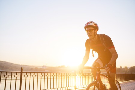 Young and energetic cyclist in the park. Man are cycling road bike by the lake in the park