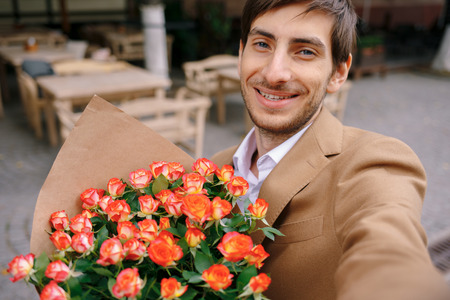 Smiling man making selfie with flowersの写真素材