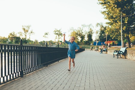 Girl playing, running with toy paper airplaneの写真素材