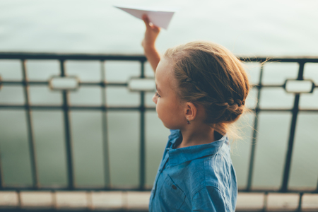Girl playing with toy paper airplaneの写真素材