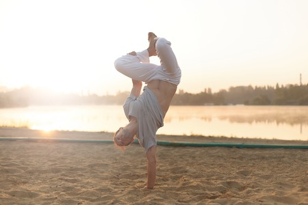 Athletic capoeira performer workout training on the beach sunrisの写真素材