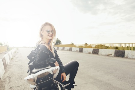 Beautiful woman posing with sunglasses on a motorbike