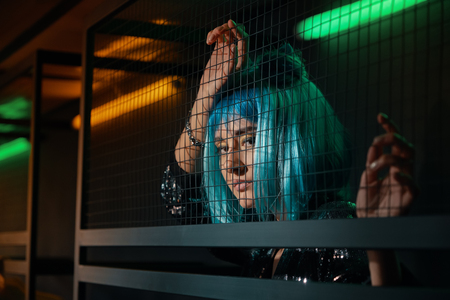 Girl standing behind metalic wire meshの写真素材