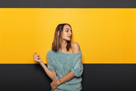 Copy space for advertisement. Colorful portrait of a happy, smiling young woman with an yellow rectangle framed by the black background in the back.  Face expressions and emotions.の写真素材