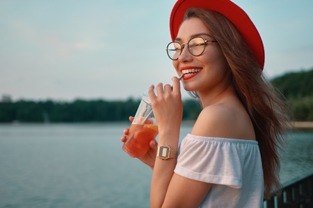 A Young stylish woman having a refreshing drink while walkingの写真素材