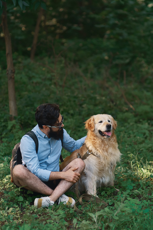 Man resting on the grass sitting crossed legs with his dogの写真素材