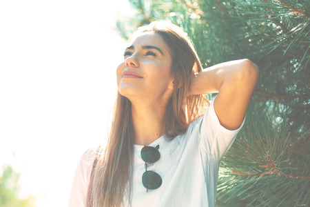 Close-up young woman with beautiful face features touching hair with hand smiles enjoying life with...