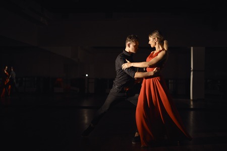 Young beautiful couple dancing with passion, light play reflected on the dancersの写真素材