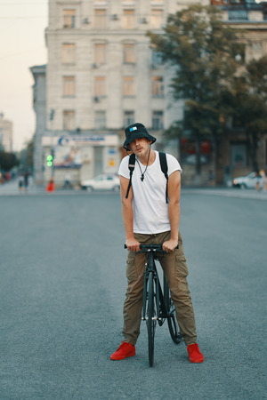 Stylish Man With Bicycle Going To Work On Street. Portrait Of Young Male In Casual Clothes With Backpack Walking On City Street With Stylish Bike. Red Sneakers.の写真素材