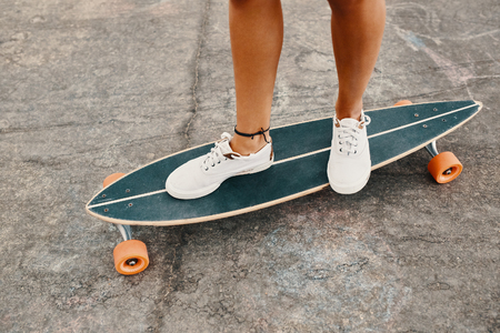Close up of woman legs in white sneakers on longboardの写真素材
