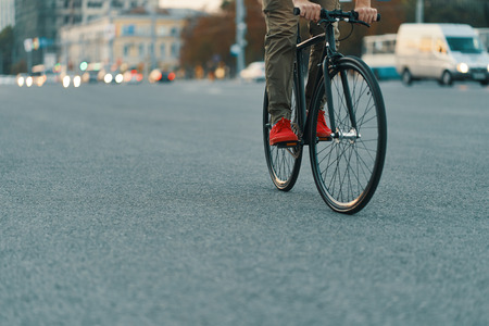 Closeup of casual man legs riding classic bike on city roadの写真素材