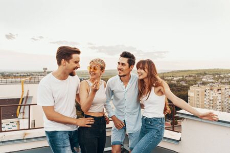 Group of friends enjoying outdoors at roof. Young friends at sunset on penthouse patio