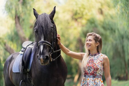 Young woman with a horse. Lady in a bright colorful dress