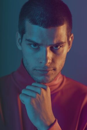 Close-up portrait of attractive male model. Retro wave portrait of a young man at studio. High Fashion male model in colorful bright neon lights. Art design conceptの写真素材
