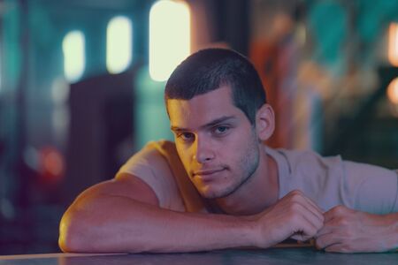 Close-up portrait of attractive male model. Retro wave portrait of a young man in a bar. Model in colorful bright neon lights.の写真素材