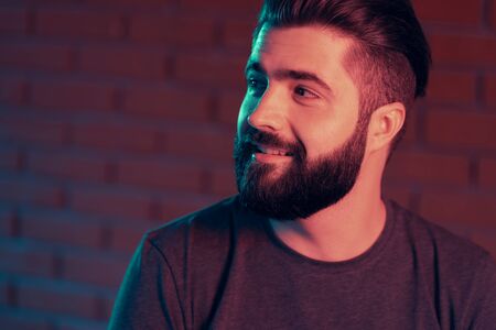Cheerful young man in a nightclub at a brick wall. Neon light