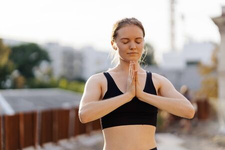 Young girl practicing stretching and yoga workout exercise on the terraceの写真素材