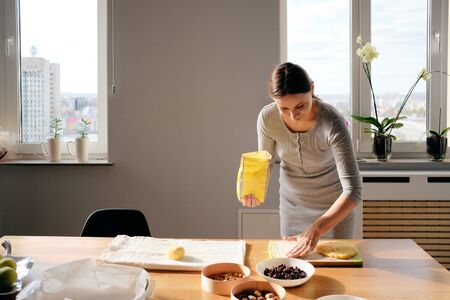 A Young beautiful woman preparing dough on a sunny day. Homemade bread, bakery while staying home.