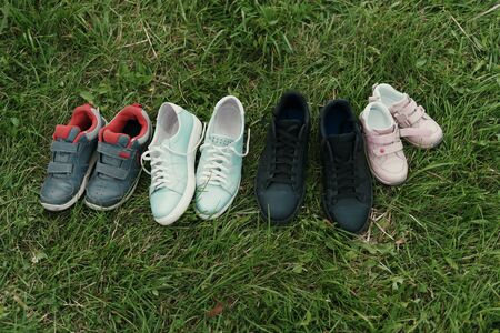 Family shoes on grass background. Four pairs of footwear on grey. Family concept
