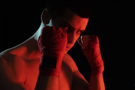 Boxer male fighter posing in confident defensive stance with hands in banndages up on black backgroundの写真素材