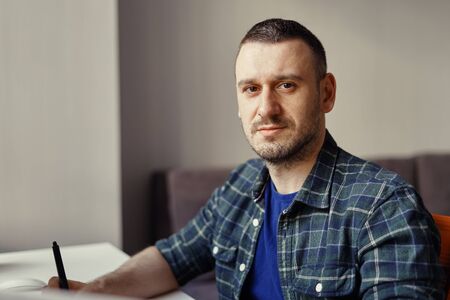 Handsome freelancer man working remotely from home. Young male holding a stylusの写真素材