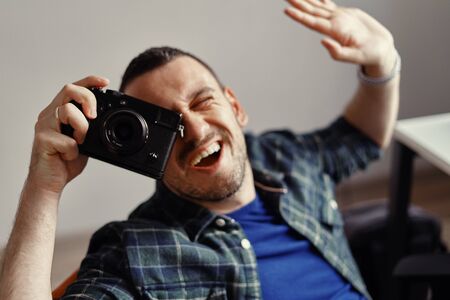 Close up Smiling Good Looking Young Male Photographer Taking Picture Facing at the Camera.の写真素材