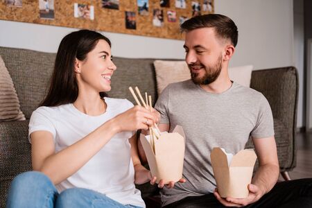 Beautiful young couple has a good time together at home while eating Chinese foodの写真素材