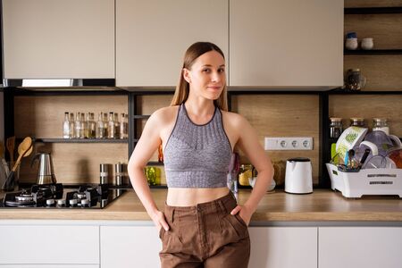 Morning atmosphere in a modern kitchen. Beautiful woman stands posing and relaxing. Modern woman kitchen conceptの写真素材