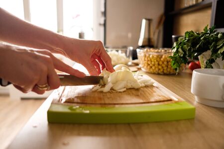 Woman hands, cutting onions while preparing ingredients for falafel. Healthy diet