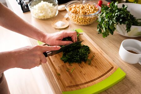 Woman hands, cutting dill while preparing ingredients for falafel. Healthy dietの写真素材