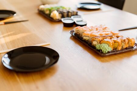 Close up of mix of sushi rolls on a table at home. Waiting friends to eat sushi rolls together using bamboo sticks.の写真素材