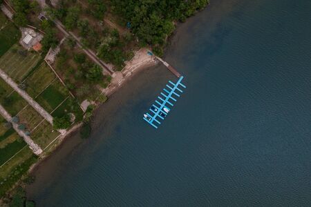 Aerial view of agricultural lands on the coast of river with green trees. Healthy and ecological...