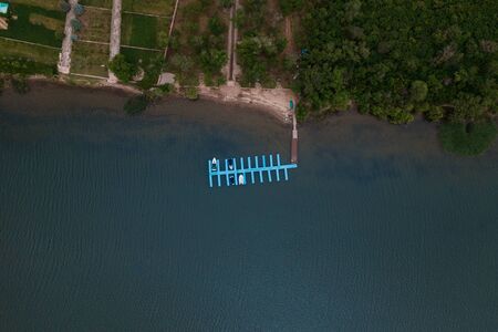 Aerial view of agricultural lands on the coast of river with green trees. Healthy and ecological...