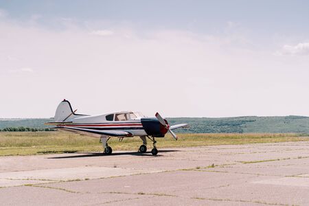 Small propeller sport airplane in the field waiting to take off with sky in background. Private airplanesの写真素材