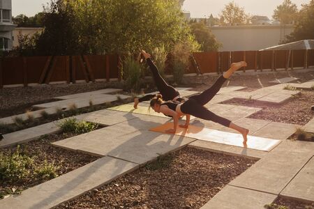Two young girls practicing stretching and yoga workout exercise together on the terraceの写真素材