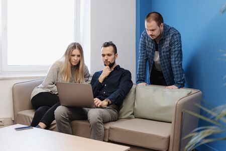 Small soft meeting area in chill out zone of office with three persons having there work meeting or conversation at the table, Two men and one womanの写真素材