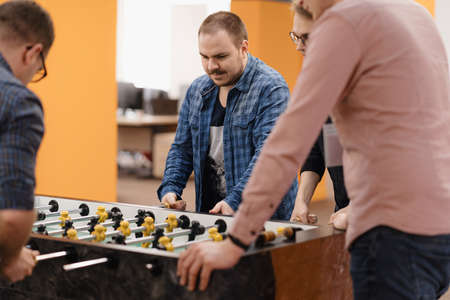 Group of Young Office Workers Playing Table Soccer Game Inside the Office During their Break time.の写真素材
