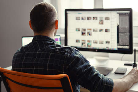 Back view freelancer man working remotely from home. Young male working on his computerの写真素材