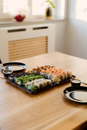 Close up of mix of sushi rolls on a table at home. Waiting friends to eat sushi rolls together using bamboo sticks.の写真素材