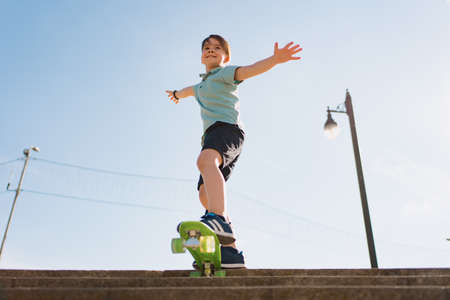 Happy young boy playing on skateboard in the park, Caucasian kid riding penny board, practicing skateboard.の写真素材
