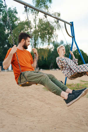 Romantic couple is having fun outside. Enjoying spending time together on a swings.の写真素材