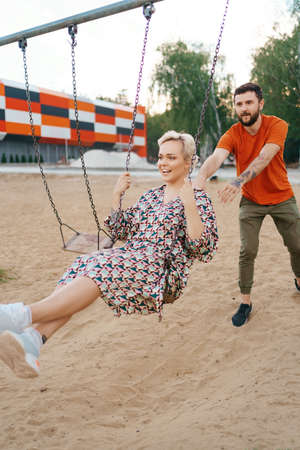 Romantic couple is having fun outside. Enjoying spending time together on a swings.の写真素材