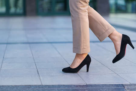 Woman wearing classic black high heel toe shoes. Model posing on the street. Elegant outfit. Close...