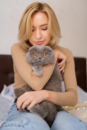 Pets, morning, comfort, rest and people concept - happy young woman with cat in bed at homeの写真素材