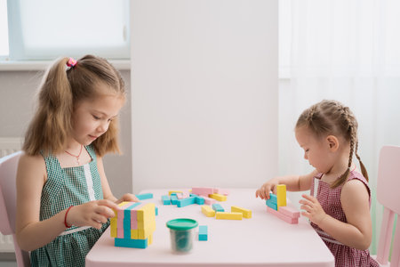 Lovely kids plaing with colorful wodden blocks in a creative educational game as they stand at a pink tableの写真素材