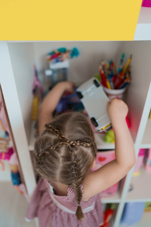 A cute little girl searching certain toy on the toy in the room with yellow copy spaceの写真素材