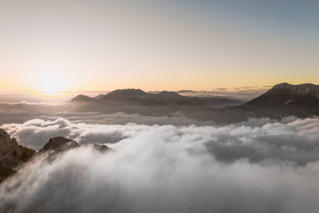 Aerial view above the cliffs and mountains meeting the sky and clouds. Picturesque landscape....